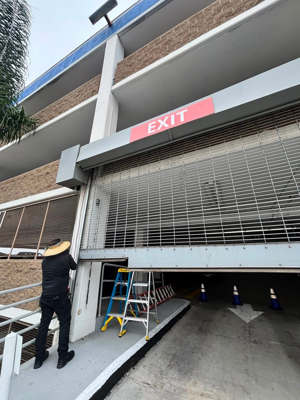 A commercial rolling steel security grille being serviced at the entrance of a multi storey parking structure